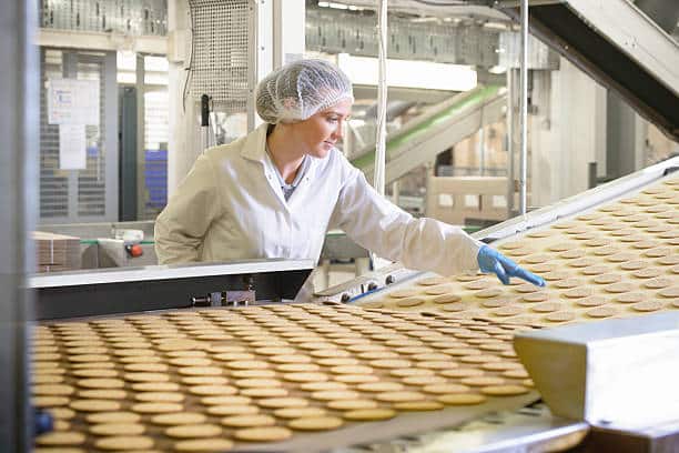 Femme qui contrôle la production de gâteaux industriels